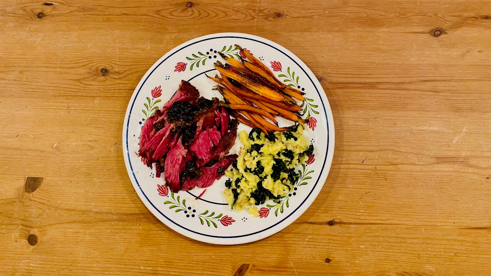 A plate with sliced corned beef, colcannon mashed potatoes and roasted carrots